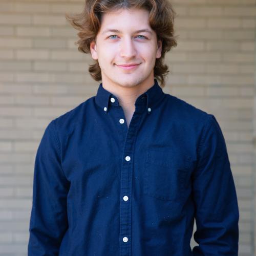 Picture of Aaron standing against a brick wall